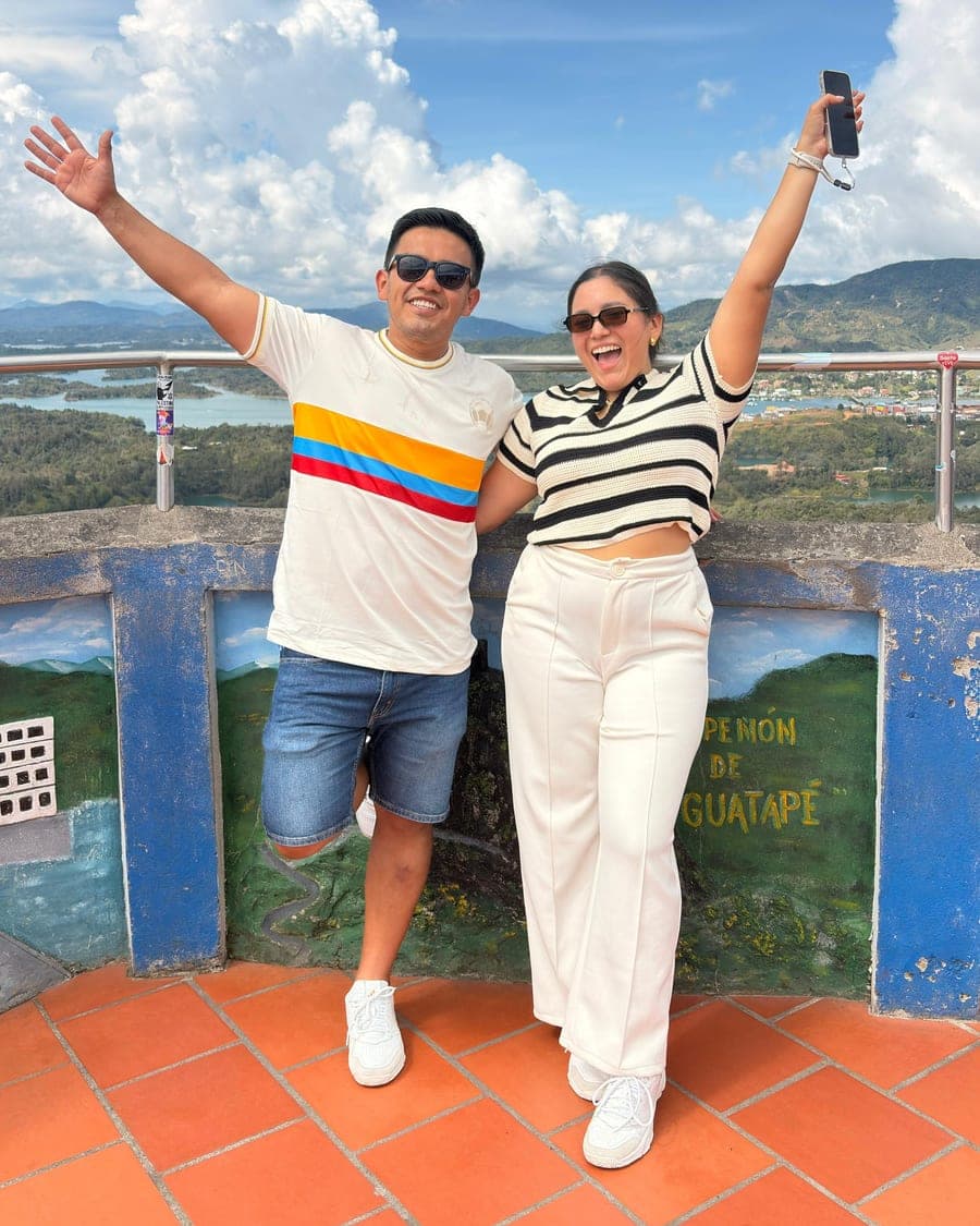 Didier y Adaylu con los brazos en alto en el mirador del Peñón de Guatapé, con el embalse al fondo