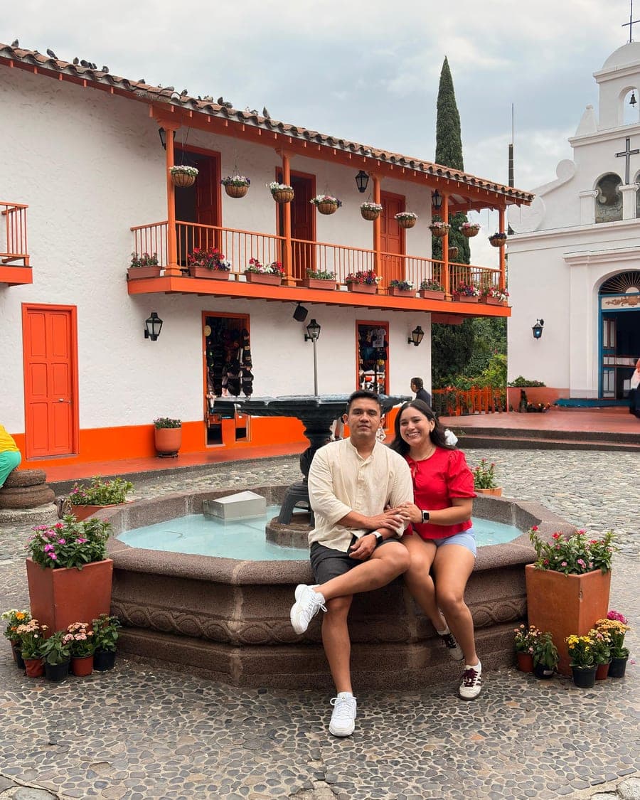 Sentados en la fuente del Pueblito Paisa, con los balcones naranjas de Medellín al fondo