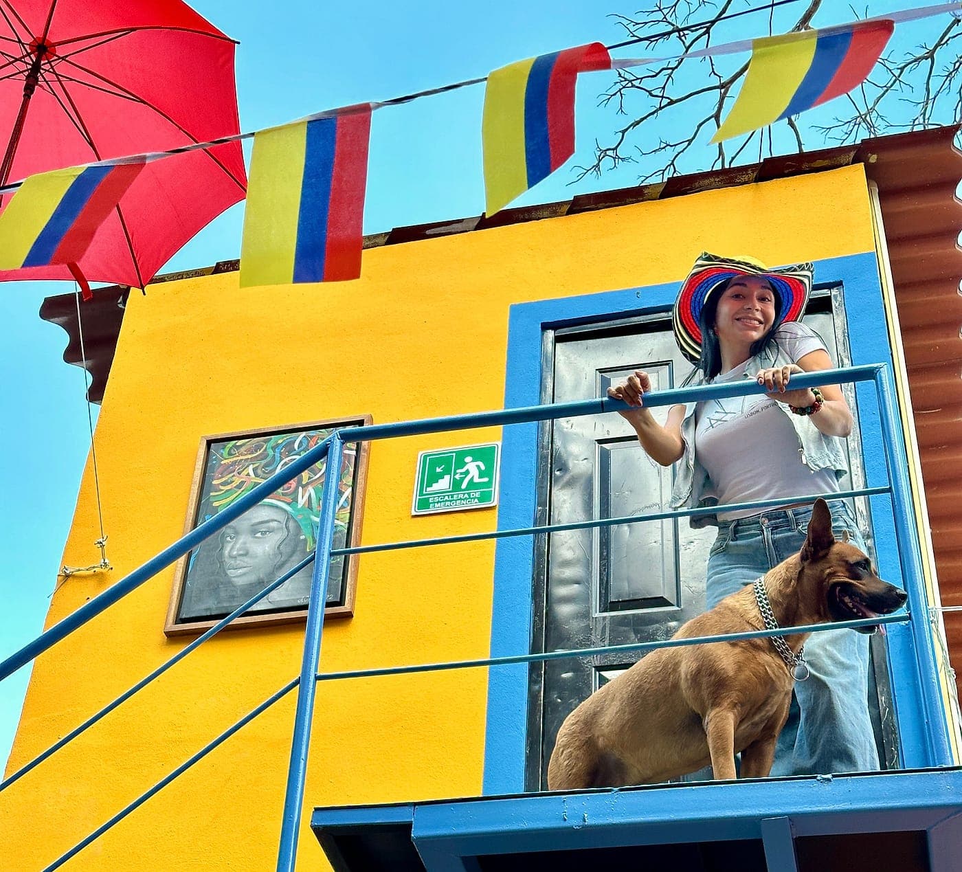 The yellow façade of Parceros with its blue balcony and Colombian bunting, two blocks from Parque de Santa Lucía.