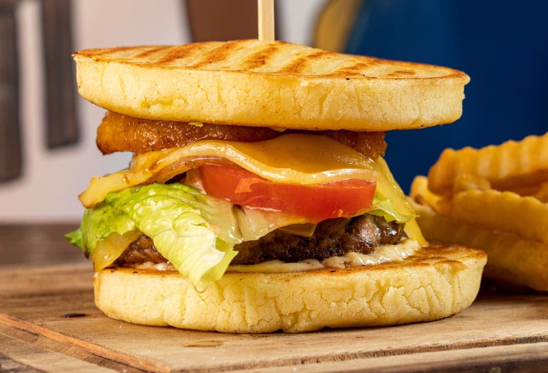 Arepaburger: Hamburguesa de res con lechuga, tomate, piña, cebolla caramelizada y más queso. Con papas a la francesa.