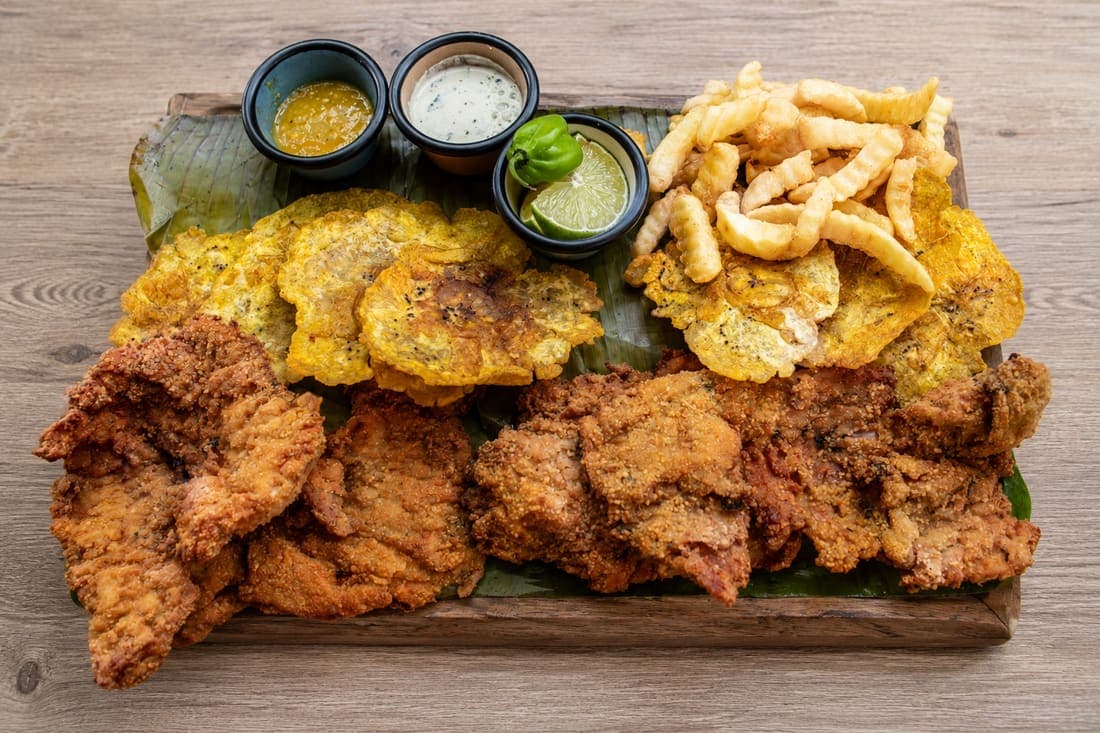 Chuleta Valluna XL: Orgullo del Valle del Cauca: cerdo tierno empanizado y frito hasta quedar crujiente • papas • patacones • aguacate.