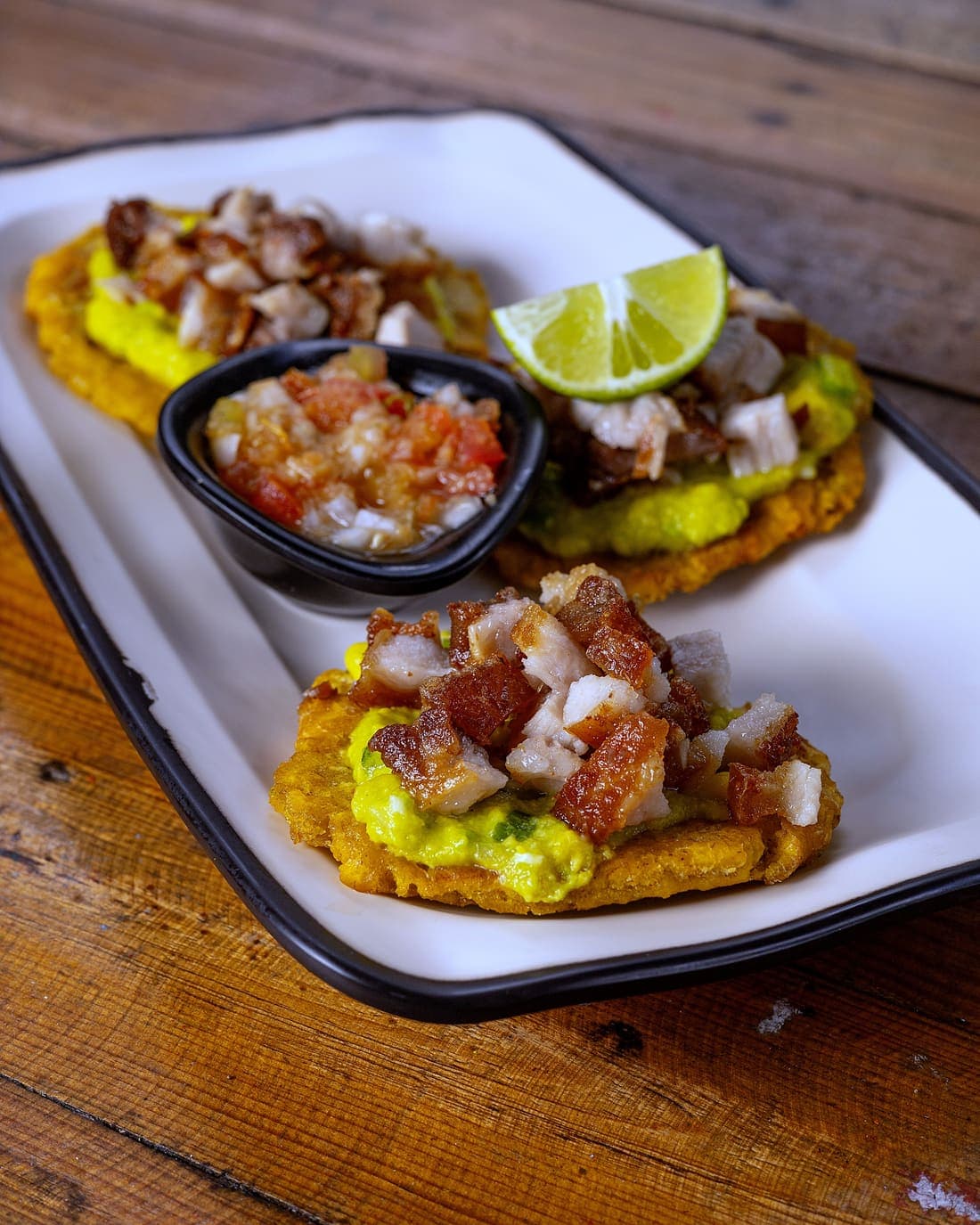Patacones con Chicharrón: Patacón dorado y crocante, cama de aguacate cremoso y chicharrón carnoso.