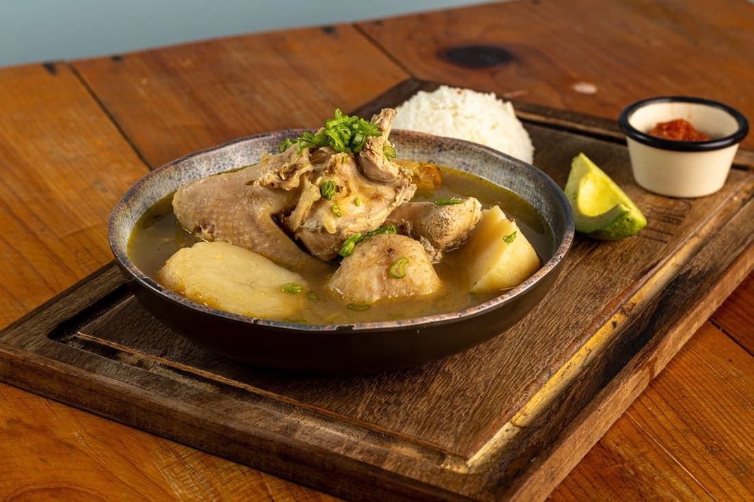 Sancocho de Gallina: Gallina criolla cocida lentamente con plátano, yuca y elote, servido con arroz y aguacate.