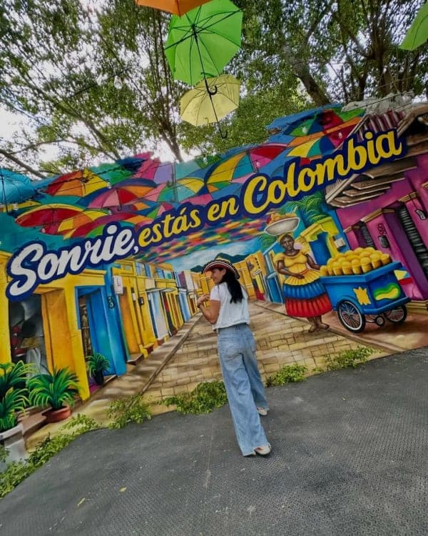 The «Sonríe, estás en Colombia» mural at the entrance to Parceros, under the ceiling of colored umbrellas.